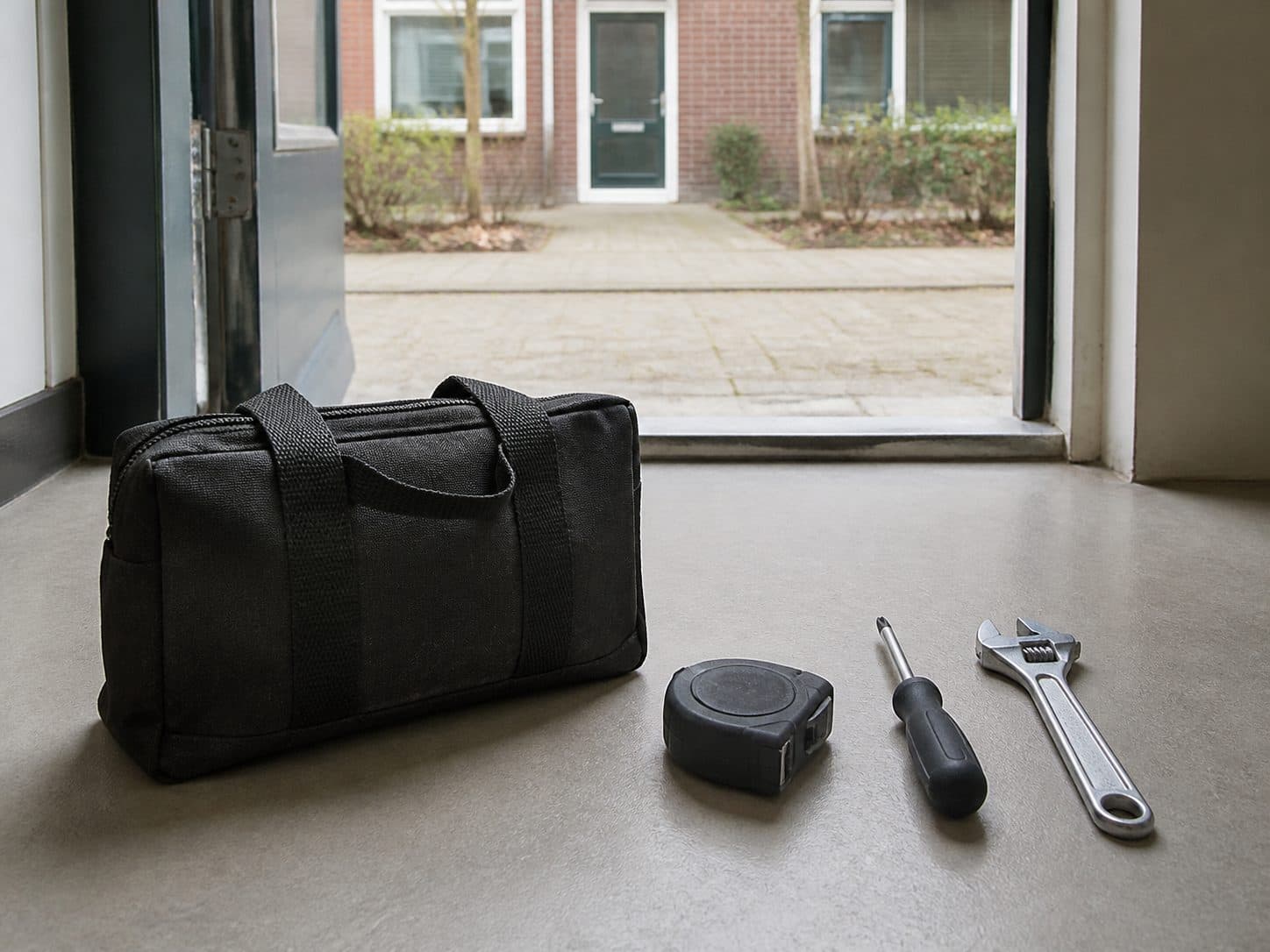 Gereedschap en een gereedschapstas klaar bij een entree.