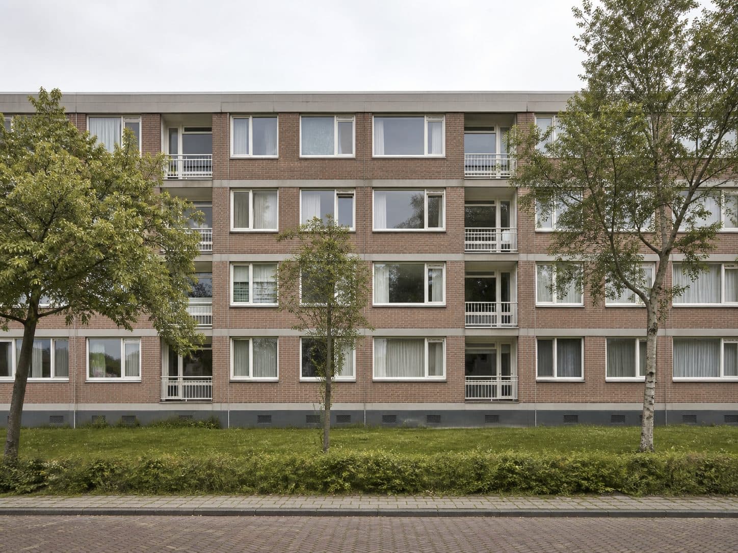 Woongebouw met meerdere woningen en volwassen bomen.